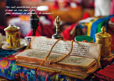 eine buddhistischer Text in Sanskrit mit einer Gebetskette und einer Teetasse