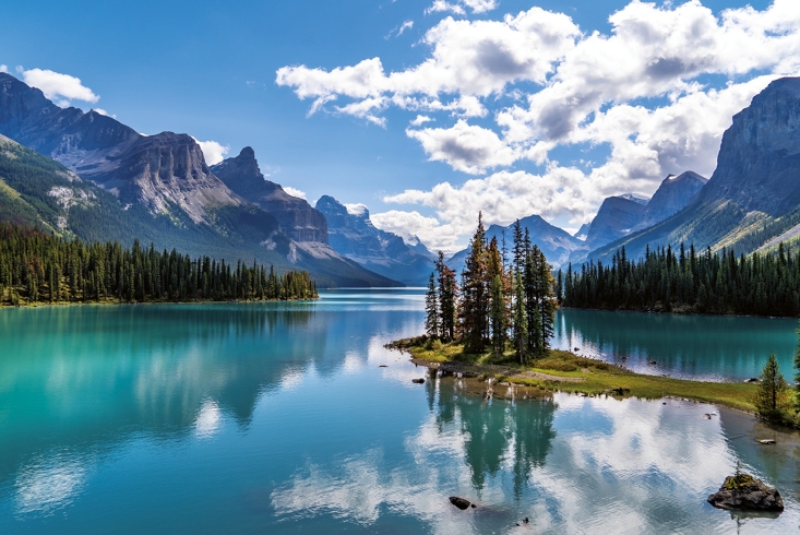 Panoramaaufnahme eines Gebirgssees. Im strahlend blauen Wasser spiegelt sich die Umgebung und der Himmel. Link führt zur Leseprobe Warum uns die Natur kreativer macht