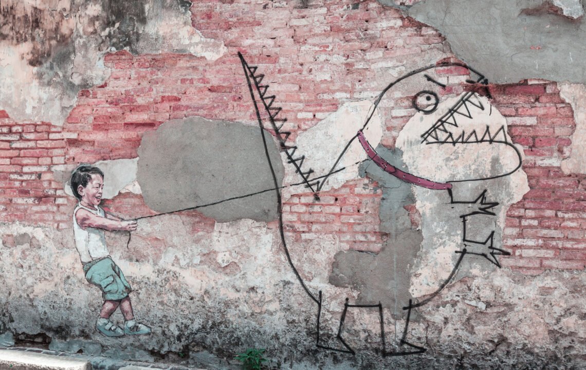 Zeichnung eines kleinen Jungen, der einen Comic-Dinosaurier an einer Leite hält als Streetart an einer Mauer. Bild dient der Illustration der Leseprobe "Achtsamkeit mit Kindern leben"